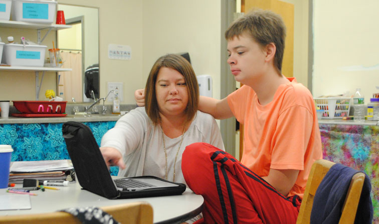 Teaching assistant pointing to chromebook screen as student looks on