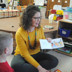 Teacher aide holds book and reads to students