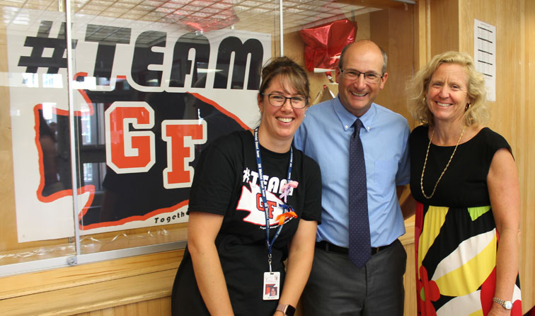 three staff members smiling in front of hashtag-TEAM GF bulletin board