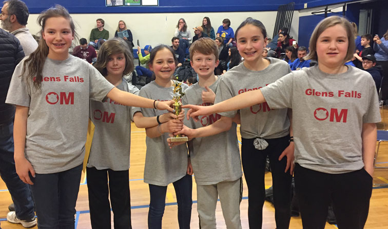 Six students in GF OM shirts smiling and holding a trophy with stars