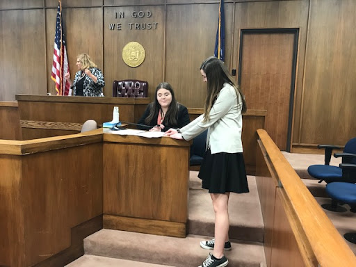 two students smiling in courtroom during mock trial