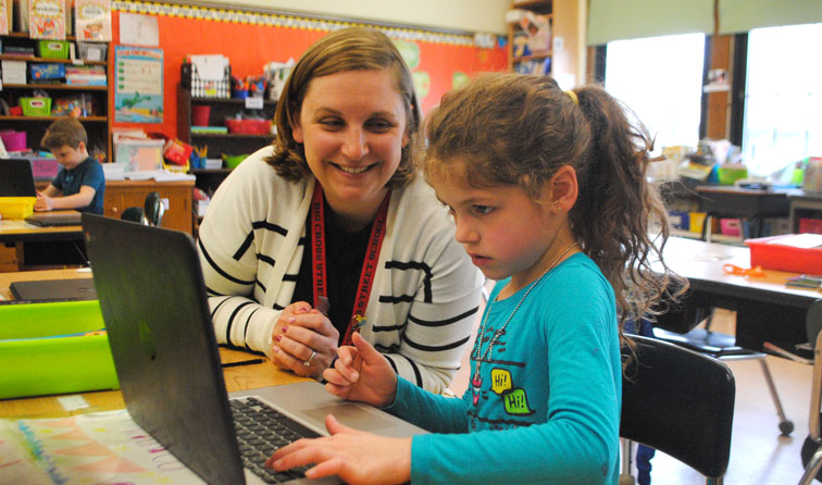 teacher and girl student working on Chromebook in colorful classroom