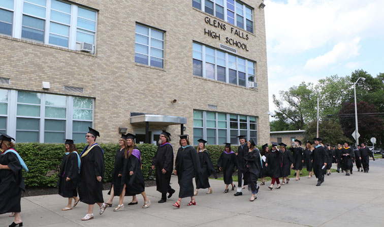 faculty members in graduation caps and gowns walk in front of GFHS