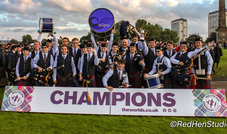 group of bagpipe players on field with champions sign in front