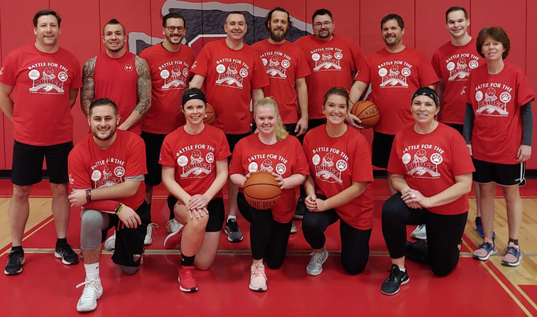 group of people in red "battle of the bridge" t-shirts holding basketball in team photo