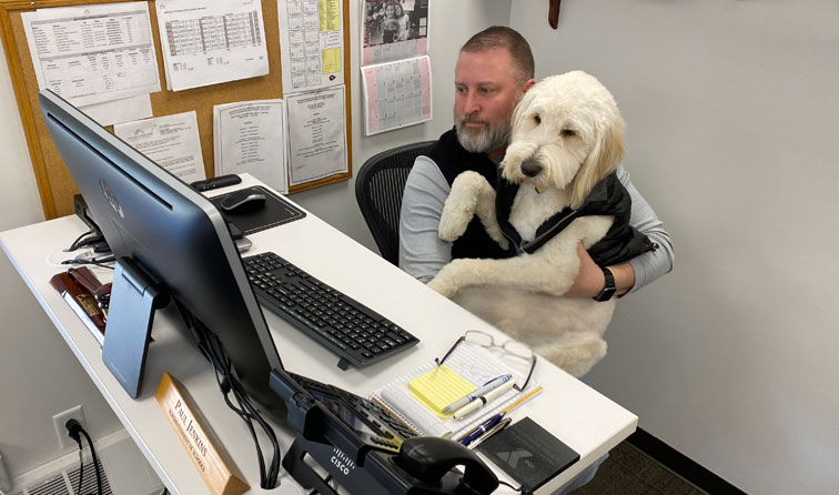 Dog and superintendent at office desk together looking at computer