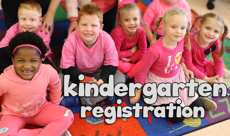 group of kindergarten students sitting on classroom rug, smiling