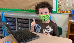 students wearing face masks back in classroom with thumbs-up