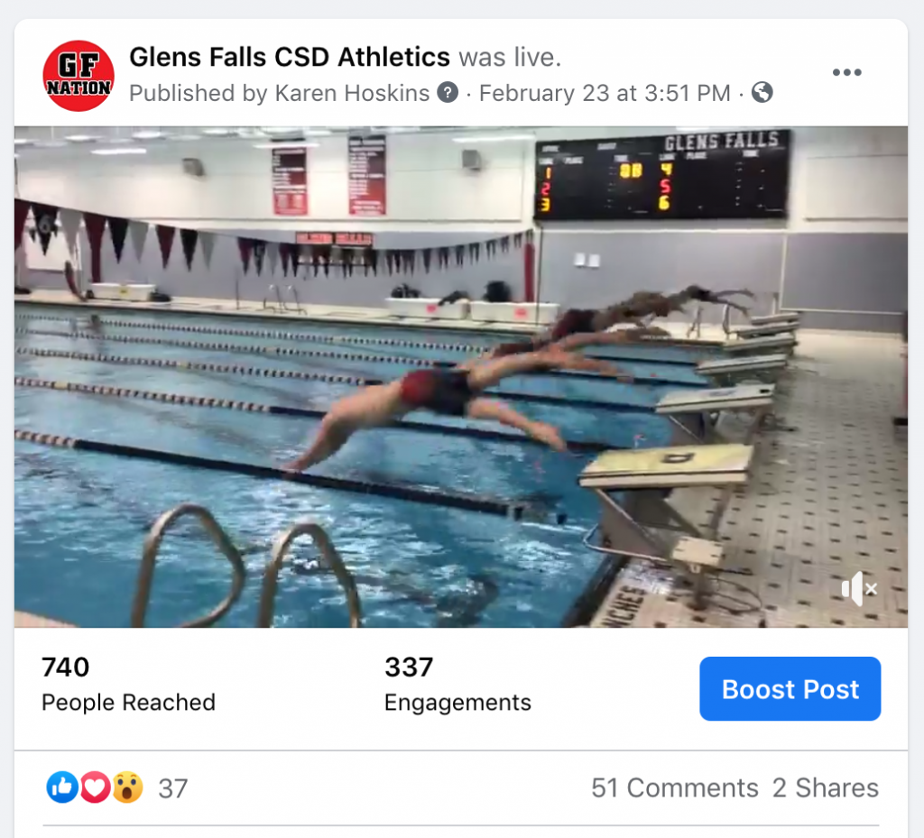 screen shot from a swim meet live stream - five boys in mid-air, diving into the school pool in unison
