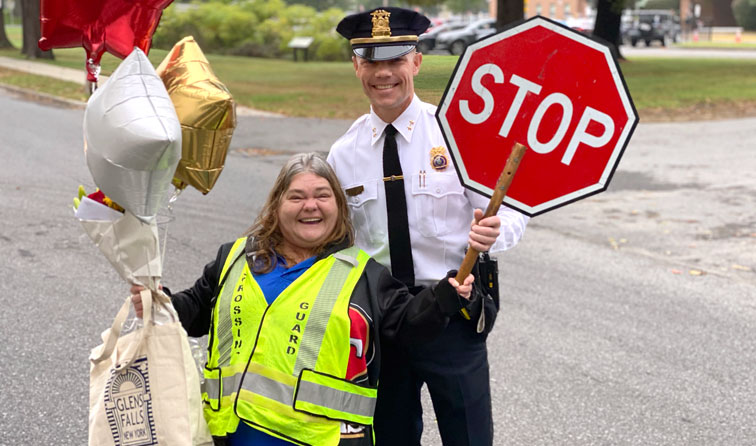 school crossing guard holding balloons smiling with second police chief in road