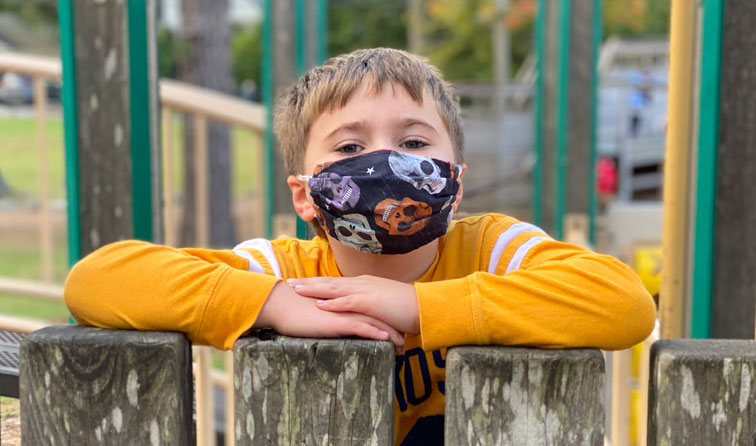 elementary student on playground smiling under mask