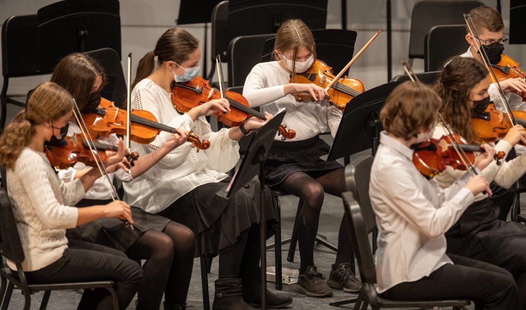 group of students playing violins on stage during a concert