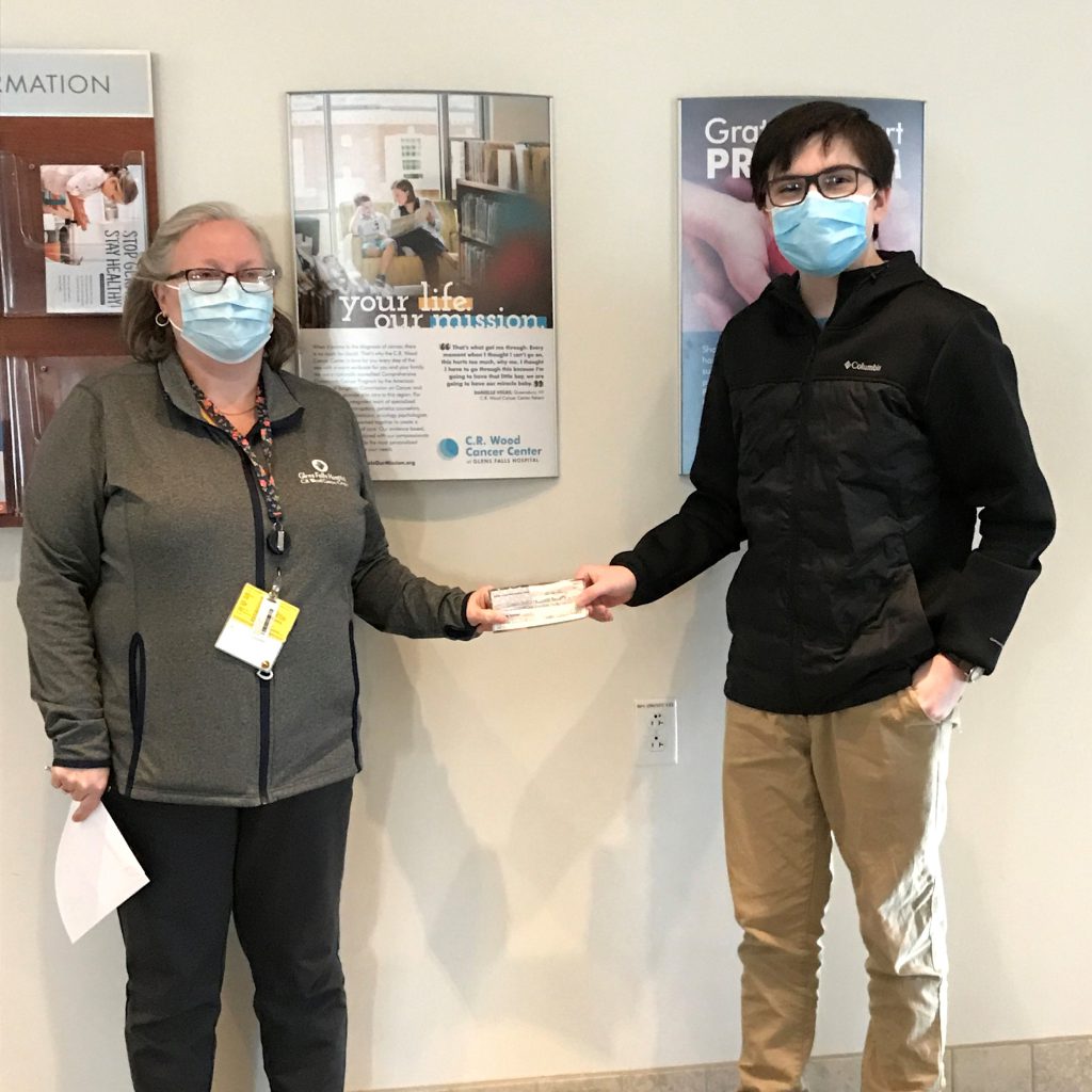 two people holding a check and smiling under masks