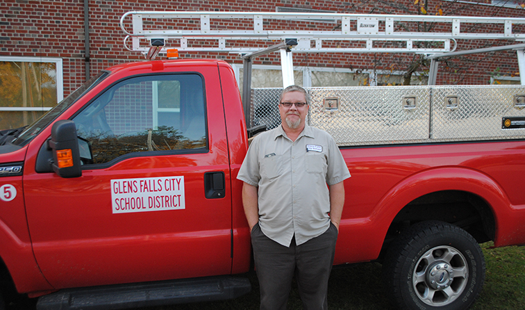 employee standing in front of a red truck reading Glens Falls City School District