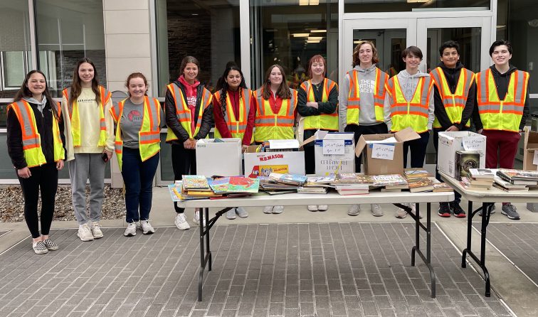group of students smiling and wearing yellow safety vests while volunteering at the Rotary 5K
