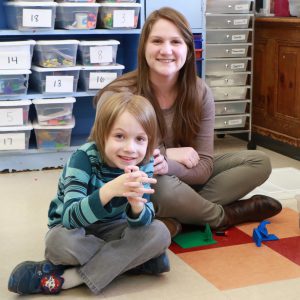 student and teacher playing with blocke smiling