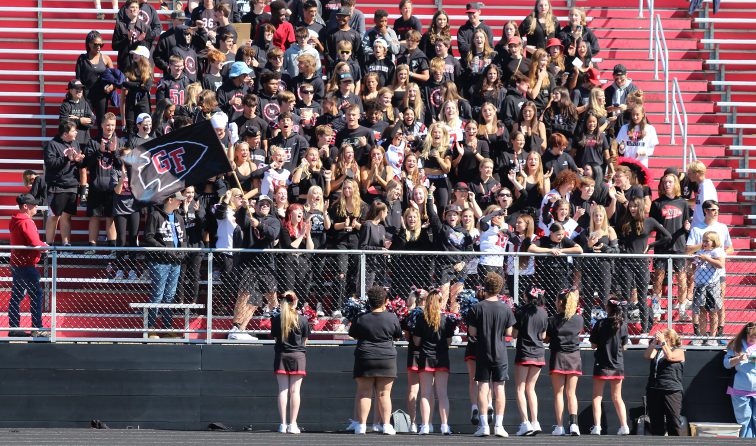 student section cheering during a sunny fall football game