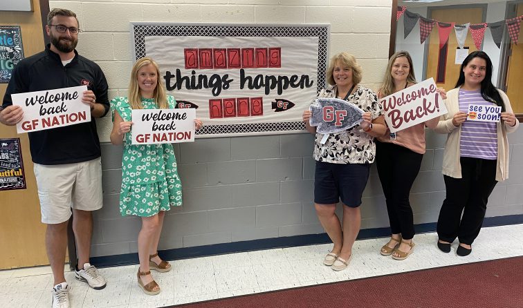 five middle school team members holding welcome back signs