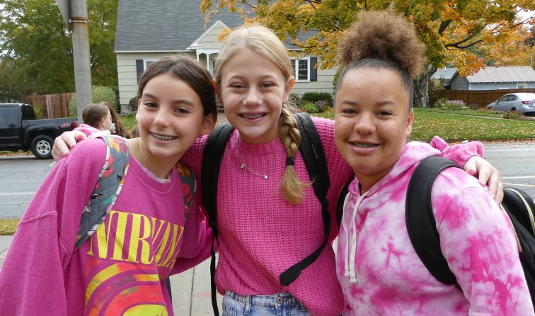 three students smiling outside wearing pink for the Power of Pink day