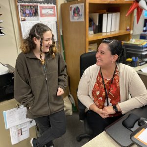 student and secretary sharing a laugh in the main office of the middle school