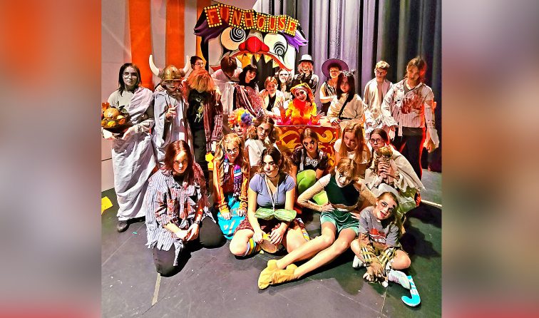HS theater and art students dressed in halloween costumes in front of the "fun house" artwork for haunted house event