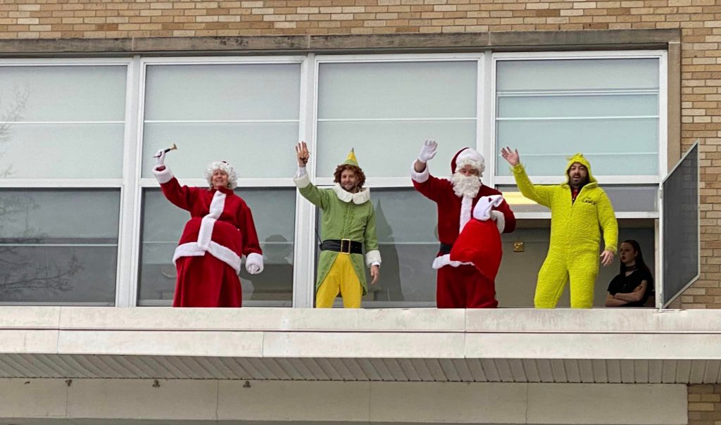 Principals dressed in holiday costumes waving to greet students coming to school