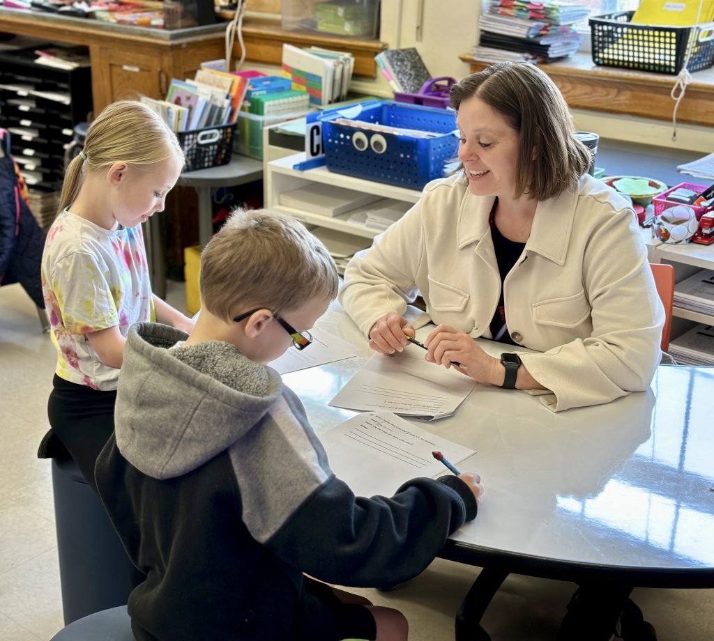 teacher working with two students in a classroom
