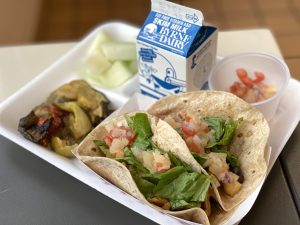 school lunch tray with Hawaiian tacos and delicious looking sides plus a carton of milk