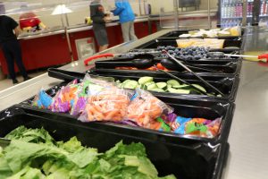 salad bar station at hte middle school cafeterai featuring lettuce, blueberries, carrots and other fresh veggies