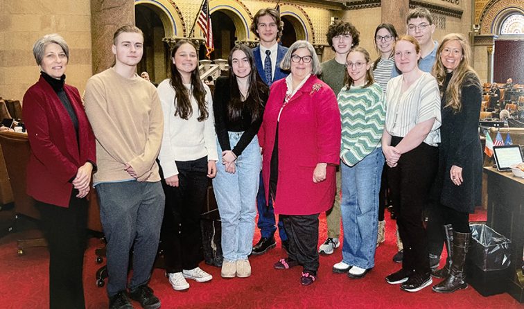 group of HS students gather on the Assembly floor with M.A. Woerner, their teacher, and the school superintendent