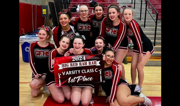 group of cheerleaders smiling in the high school gym while holding a sign that reads 2024 Big Red Rah Rah Varsity Class C 1st Place
