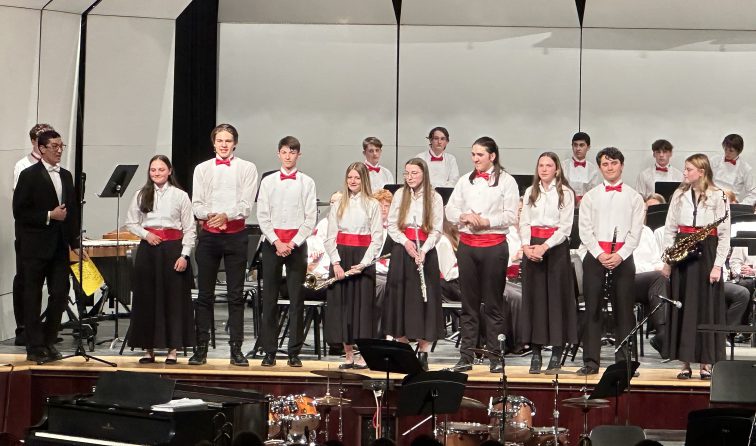 group of high school band seniors in concert dress onstage at their spring concert