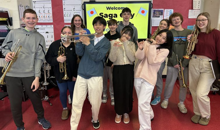 group of GF musicians with Saga exchange students holding trumpets during band class